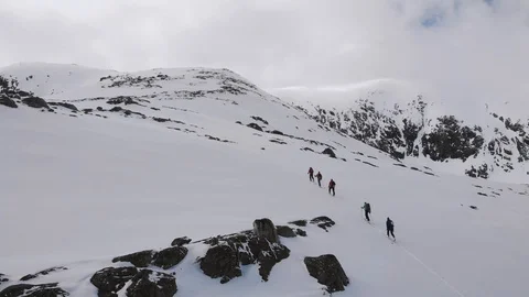 Five men ascending a mountain with skis in Norway aerial rear view Stock Footage 99772528