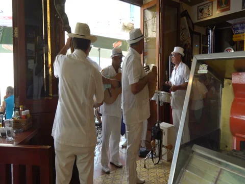 Five men musicians dressed in white suits and hats sing, play the guitar, guiro, Stock Footage 69499546