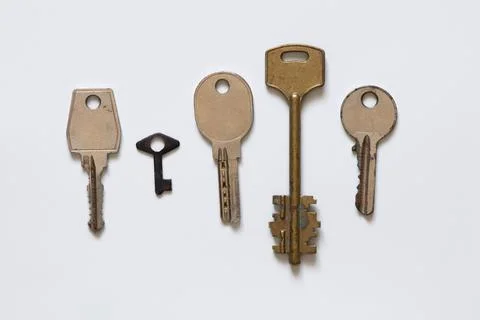 Five metal keys of different shapes and sizes old and arranged in a row on .. Stock Photos
