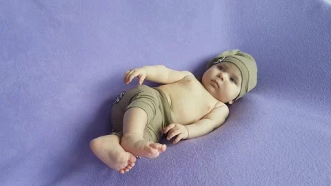 A five-month-old boy in a beige gnome suit with a naked torso Stock Footage 157126563