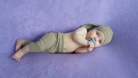 A five-month-old boy in a beige gnome suit with a naked torso Stock Footage 157126566
