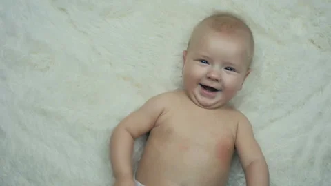 Five month old boy is lying on a blanket and smiles at the camera in slow motion Stock Footage 100578285
