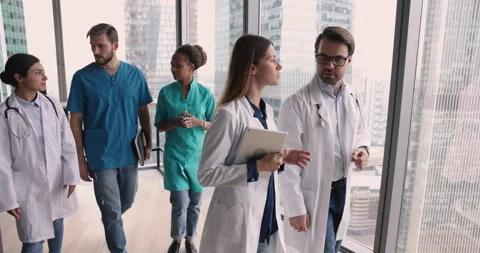 Five motivated multinational therapists talking walking along clinic hallway Stock Footage 253132384