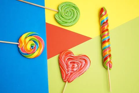 Five multi-colored lollipops of different shapes on a geometric background of Stock Photos