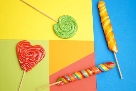 Five multi-colored lollipops of different shapes on a geometric background of Stock Photos