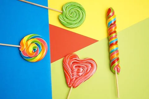 Five multi-colored lollipops of different shapes on a geometric background of Stock Photos