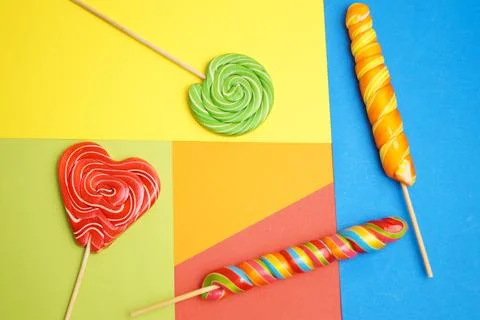 Five multi-colored lollipops of different shapes on a geometric background of Stock Photos
