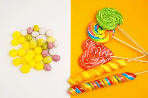 Five multi-colored lollipops on a stick. Multi-colored dragees. On a two-tone Stock Photos