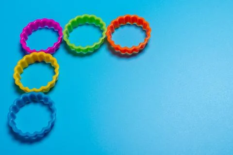 Five multi-colored plastic cookie cutter for making cookies on a blue backgro Stock Photos