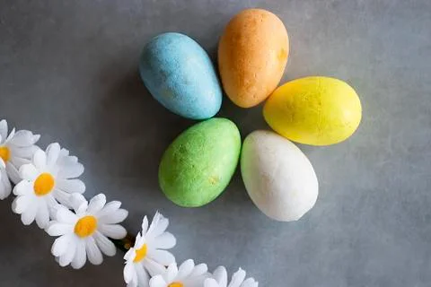 Five multicolored decorative eggs and decorative flowers on  gray background. Stock Photos