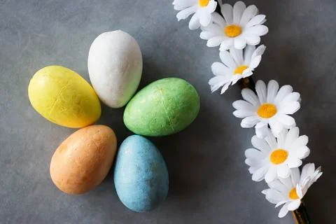 Five multicolored decorative eggs and decorative flowers on  gray background. Stock Photos