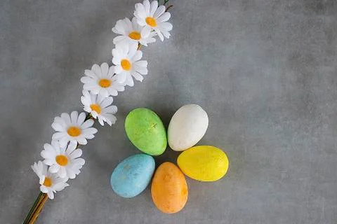 Five multicolored decorative eggs and decorative flowers on  gray background. Stock Photos