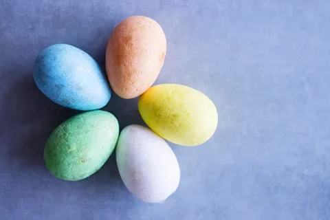 Five multicolored decorative eggs on a gray background. Top view. Stock Photos
