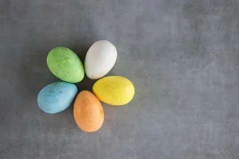 Five multicolored decorative eggs on a gray background. Top view. Stock Photos
