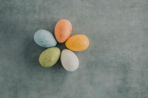 Five multicolored decorative eggs on a gray background. Top view. Stock Photos