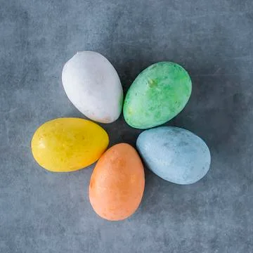 Five multicolored decorative eggs on a gray background. Top view. Stock Photos