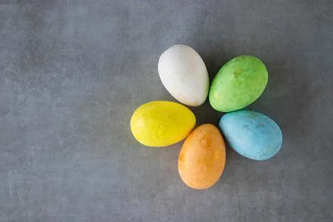 Five multicolored decorative eggs on a gray background. Top view. Stock Photos