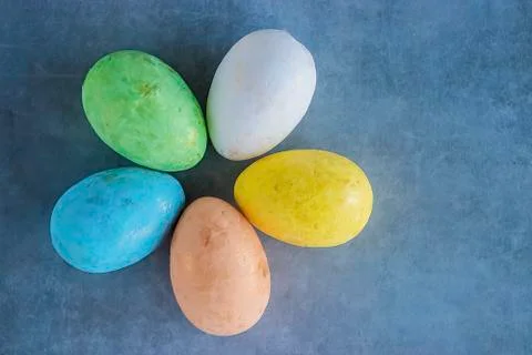 Five multicolored decorative eggs on a gray background. Top view. Stock Photos