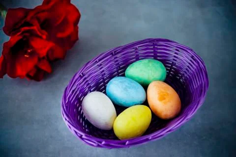 Five multicolored decorative eggs in  purple basket, two decorative rabbits a Stockfoto's
