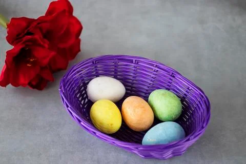 Five multicolored decorative eggs in  purple basket, two decorative rabbits a Stock Photos