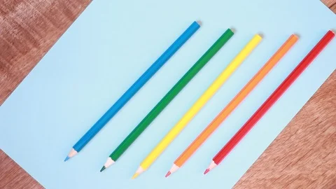 Five multicolored pencils over blue paper Vídeos de archivo 100820468