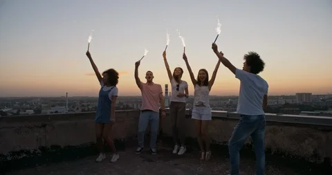 Five multiethnic friends having a summer rooftop party, dancing with sparklers Stock Footage 94718953