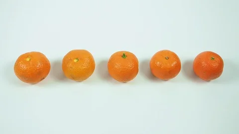 Five orange tangerine peeling by itself in rotation on a white table. Stock Footage 129574135