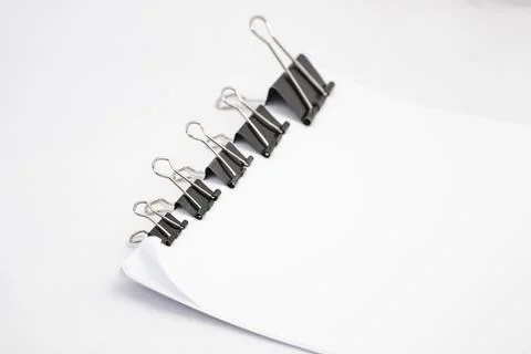 Five paper clips holding a stack of white paper, arranged side view with co.. Stock Photos