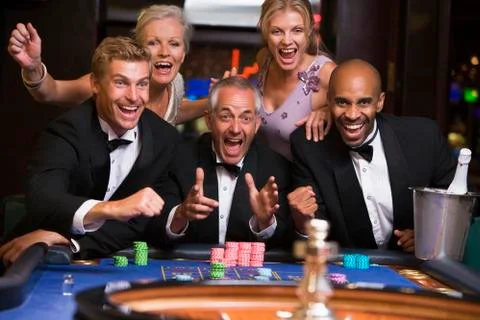 Five people in casino playing roulette smiling (selective focus) Stock Photos