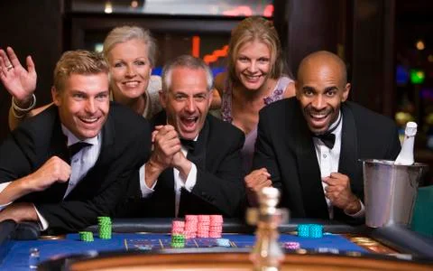 Five people in casino playing roulette smiling (selective focus) Stock Photos