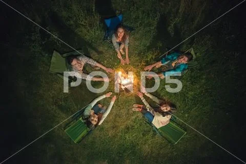 The five people hold hands near the bonfire. night time, view from above Stock Photos