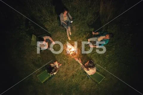 The five people sit near the bonfire. night time, view from above Stock Photos