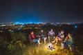 The five people sit near the bonfire on the background of the city. night tim Photo