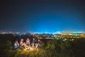 The five people sit near the bonfire on the background of the city. night tim Photo