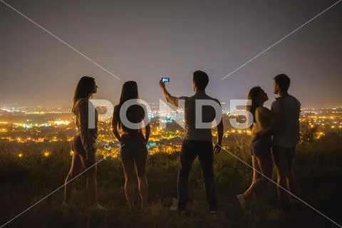 The five people stand on the background of the city and make selfie. night ti Stock Photos