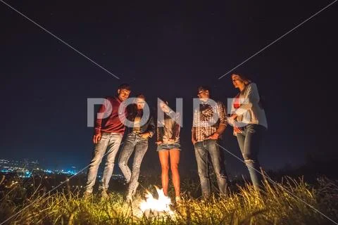 The five people stand near the bonfire on the background of the city. night t Stock Photos