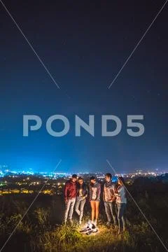 The five people stand near the bonfire on the background of the city. night t Stock Photos