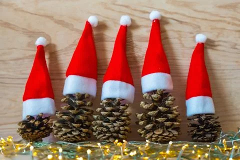 Five pine cones in a red Santa hats like a Christmas tree on a wooden background Stock Photos