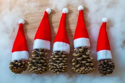 Five pine cones in a red Santa hats like a Christmas tree on a wooden background Stock Photos