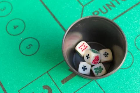 Five poker dices inside beaker on the green casino field Stock Photos