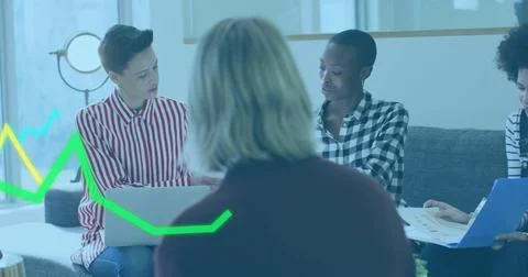 Five professionals wearing patterned tops in office lounge, reviewing charts and Stock Photos