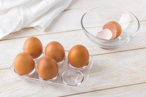 Five raw chicken eggs in a transparent plastic tray and empty eggshell. Foto stock