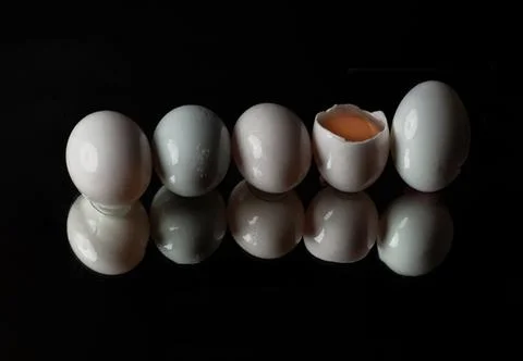 Five raw duck eggs are sitting in a row with an egg broken in half showing .. 写真素材