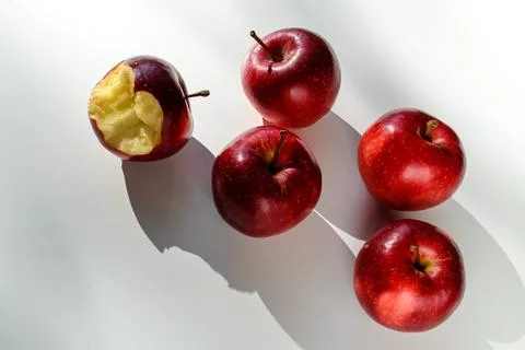 Five red ripe apples lying on a white table and their shadows Fotos de archivo