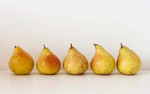 Five ripe yellow pears on a table on a white background Stock Photos