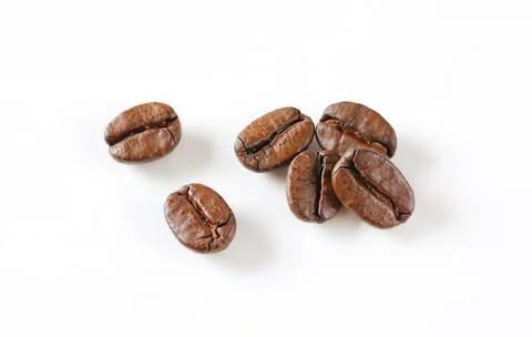 Five roasted coffee beans on plain surface Stock Photos
