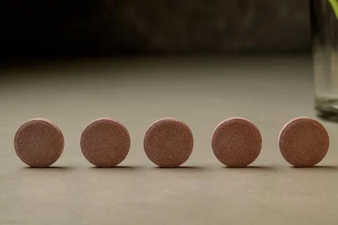 Five round wellness tablets lined up on a neutral surface for health focus Stock Photos