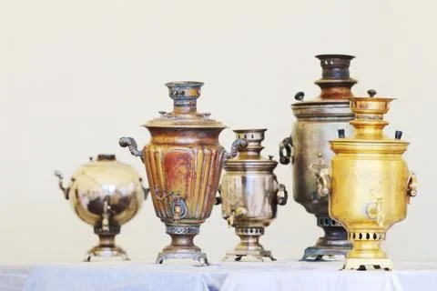 Five Russian samovars of different shapes and sizes are on table with blue ta Stock Photos