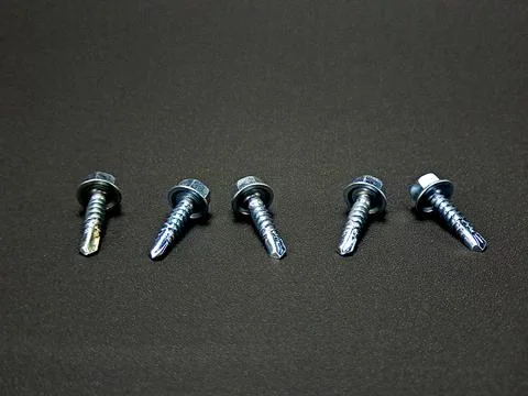 Five self-drilling screws aligned on a dark surface create a pattern of har.. Stock Photos