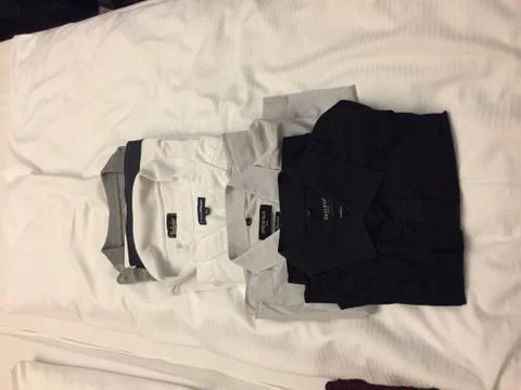 Five shirts lying on a bed. Stock Photos